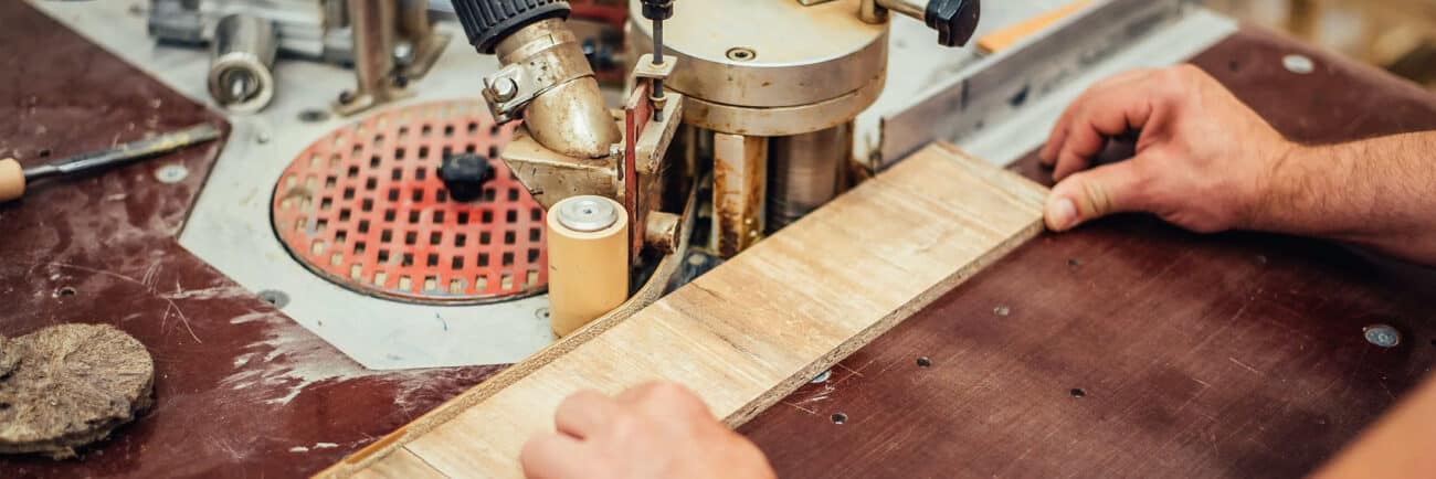 man applying wood veneeer edge banding using edge banding machine